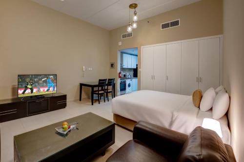 a bedroom with a bed and a couch and a tv at City Stay Residences - Serviced Apartments DIP in Dubai