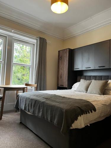a bedroom with a large bed and a table and windows at Norwood Guesthouse-Loch Lomond in Balloch