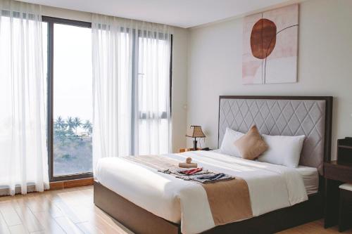 a bedroom with a large bed and large windows at KIKOZO DA NANG Hotel in Da Nang