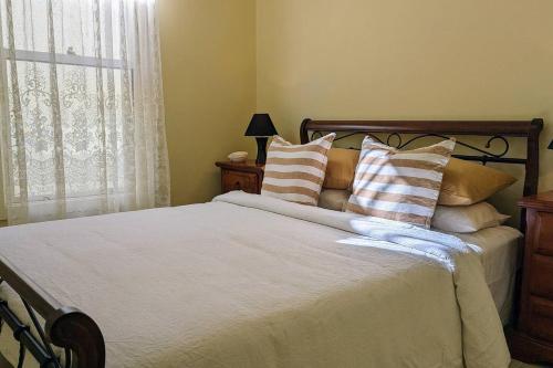 a bedroom with a bed with pillows and a window at Learmonth Guesthouse - Queenscliff in Queenscliff