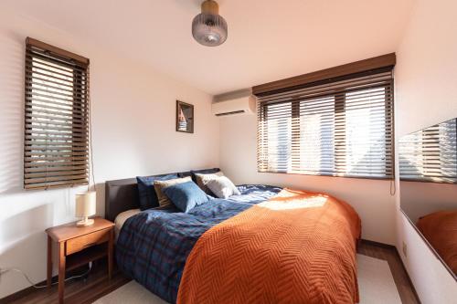 a bedroom with a bed and two windows at LiveGRACE Hotel Shibuya 渋谷西新宿 in Tokyo