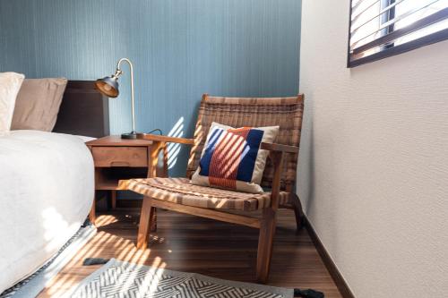 a bedroom with a bed and a chair with a pillow at LiveGRACE Hotel Shibuya 渋谷西新宿 in Tokyo