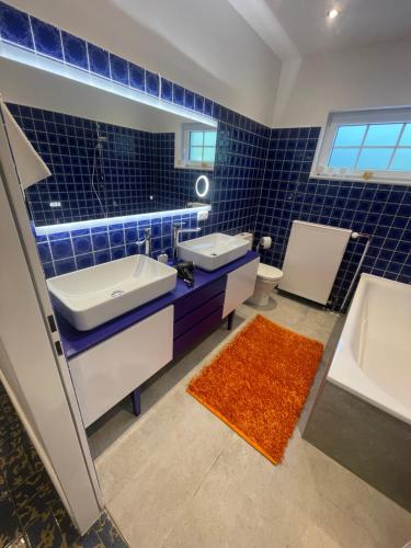 a blue tiled bathroom with two sinks and a tub at Exklusiv Villa bei Hamburg 