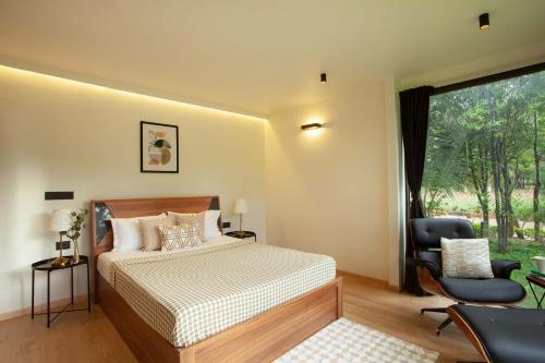 a bedroom with a bed and a chair and a window at StayVista at Cargo Haus The Luxury Collection in Bangalore