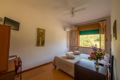 - une chambre avec un lit et un vase de fleurs sur une table dans l'établissement Hotel La Feluca, à Portoferraio