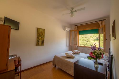 a bedroom with a bed and a vase of flowers on a table at Hotel La Feluca in Portoferraio
