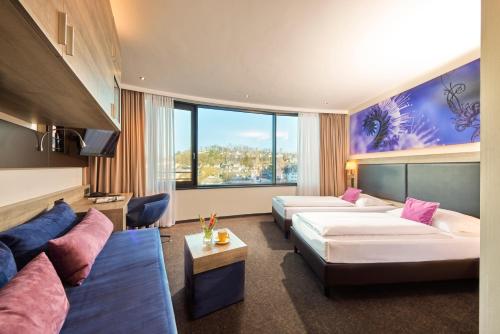 a hotel room with two beds and a couch at Hanse Hotel Attendorn in Attendorn