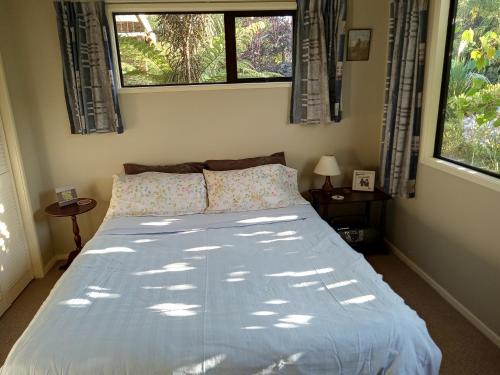 a bedroom with a large bed with two windows at Gateway to Abel Tasman Park & Kaiteriteri. in Umukuri