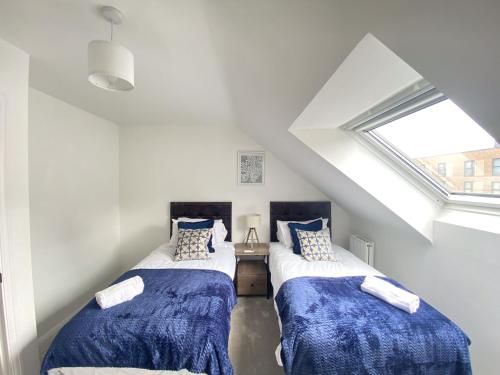 two beds in a attic room with a window at Trade Stays Welcome Secure Parking Large Townhouse Long Stay Savings Available just Ask! in Birmingham