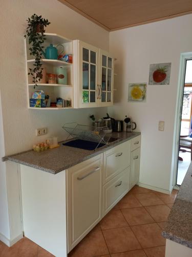 une cuisine avec des placards blancs et un comptoir dans l'établissement Das kleine Haus, à Hornburg