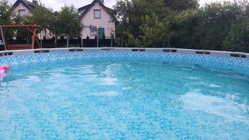 a large pool with blue water in front of a house at Dworek Łeba in Łeba