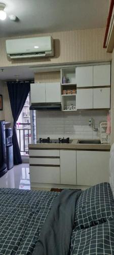 a kitchen with white cabinets and a bed in a room at Puri Park View in Jakarta