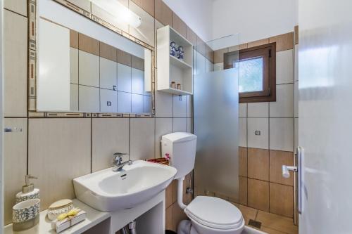 y baño con lavabo, aseo y espejo. en Lemon Casa, en Skopelos Town