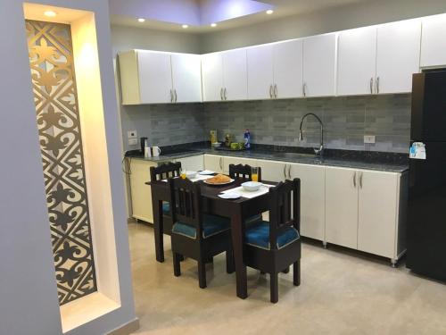 cocina con mesa, sillas y fregadero en Villa Elkoumy Apartments en Luxor