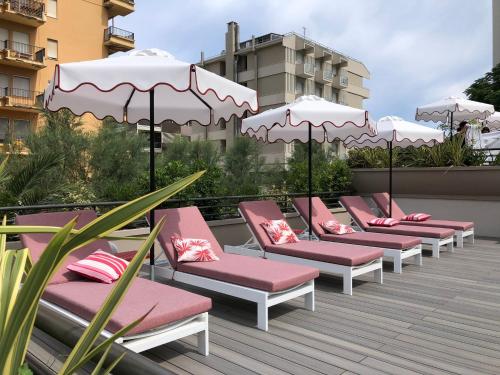 une rangée de chaises avec parasols sur une terrasse dans l'établissement Charlie in Pesaro, à Pesaro