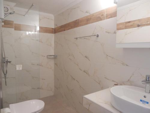 a white bathroom with a sink and a shower at Flamingo in Hanioti
