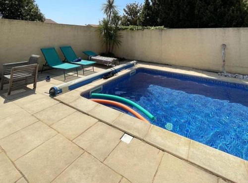 une piscine avec deux chaises et une piscine dans l'établissement Villa Agda, à Agde