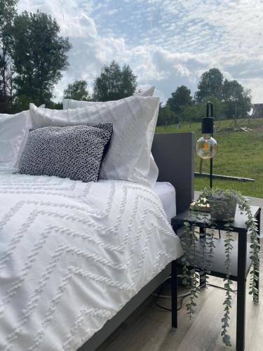 een bed met een wit dekbed en kussens op een veranda bij La bulle du Bon'Heure in Somme-Leuze