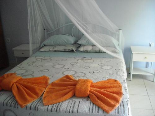 a bed with two orange bow ties on it at Maritsas Apartments in Roda