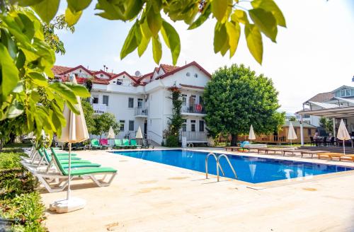 una piscina in un hotel con sedie e ombrelloni di Tugay Hotel a Fethiye