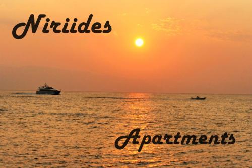 two boats in the ocean at sunset at Niriides Apartments in Porto Heli