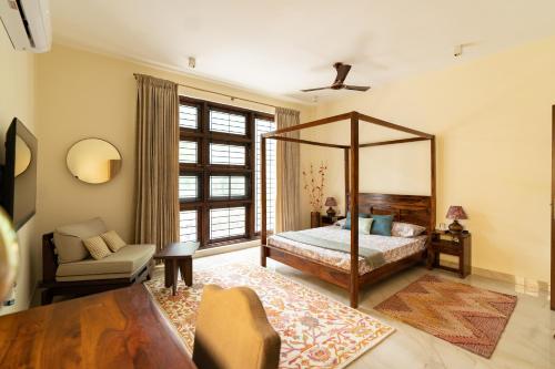 1 dormitorio con cama con dosel y silla en Luho 125, en Bangalore