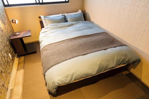 a bed in a small room with a window at Guesthouse Kobe Nadeshikoya in Kobe