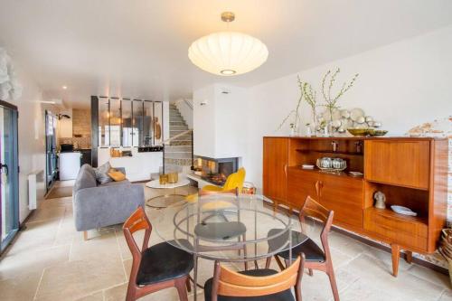 un salon avec une table en verre et des chaises dans l'établissement Maison chaleureuse en centre village avec cheminée, à Vézinnes