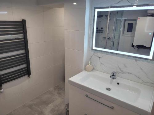 a bathroom with a white sink and a mirror at Apartament NIKOLA in Wadowice