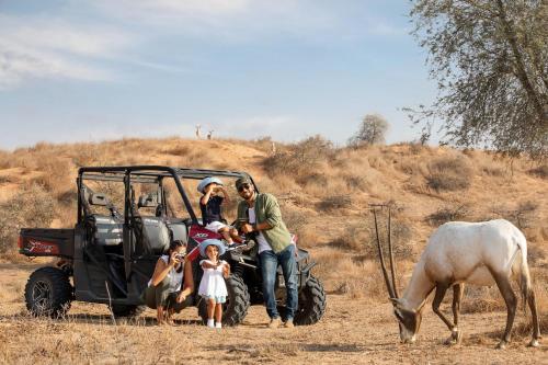 a group of people standing on a tractor with a horse at The Ritz-Carlton Ras Al Khaimah, Al Wadi Desert in Ras al Khaimah