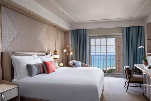 a bedroom with a large white bed and a window at The Ritz-Carlton Naples in Naples