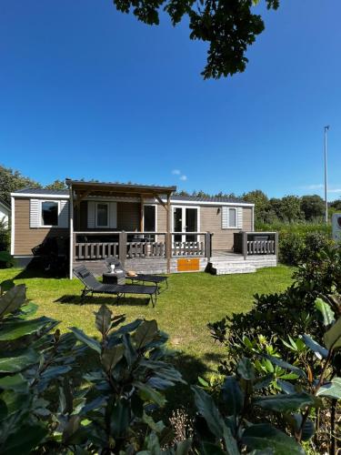 a manufactured home with a deck and a yard at De Strandhoed Renesse, new & luxe chalet with garden en close to centrum & beach! in Renesse