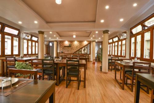 HOTEL INDIANA في شيلونغ: مطعم بطاولات وكراسي خشبية ونوافذ