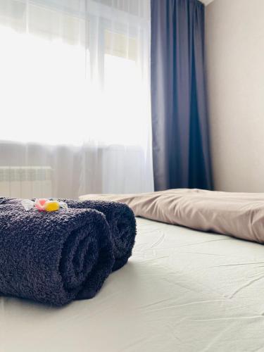 - une serviette bleue assise sur un lit et une fenêtre dans l'établissement 1-комнатная квартира, à Pavlodar