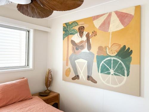 une peinture représentant un homme assis sur une chaise dans une chambre dans l'établissement The Beach House on Bribie Island, à Woorim