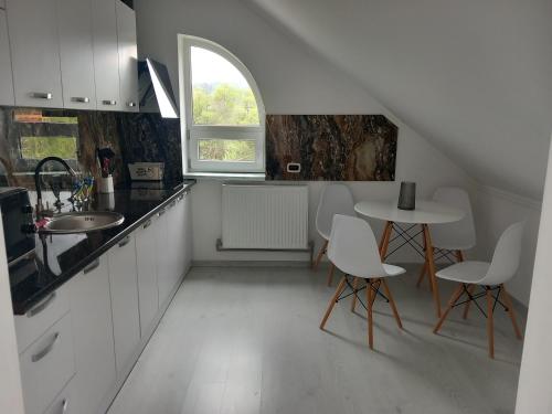 a kitchen with white cabinets and a table and chairs at Садиба "Віталія" in Volovets