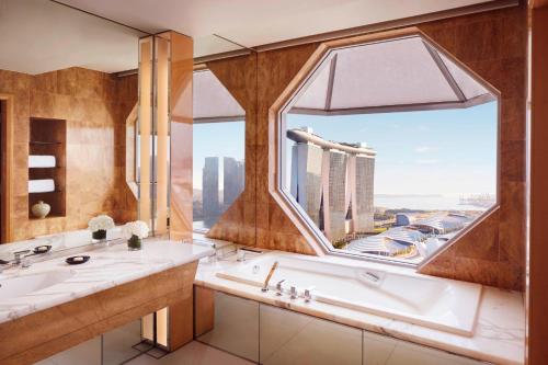 uma casa de banho com banheira e uma grande janela em The Ritz-Carlton, Millenia Singapore em Singapura