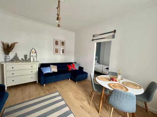 a living room with a table and a blue couch at Sailor Apartment by Marina Old Town for 8 people, free parking! in Gdańsk