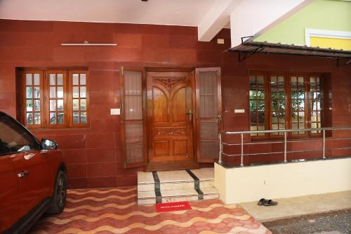 a house with a wooden door and a car parked in front at The Nest Lovely 3BHK and 1BHK Villa in Chennai