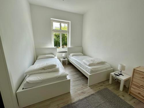 Duas camas num quarto branco com uma janela em Kröpi 8 em Bad Doberan