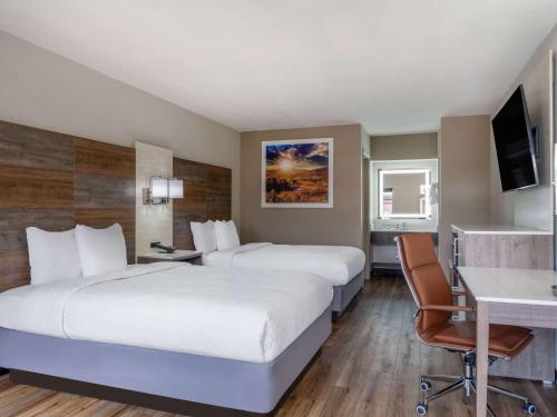 a hotel room with two beds and a desk at Days Inn by Wyndham Clemson in Clemson