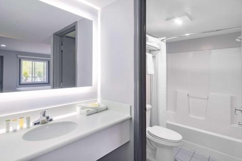 a bathroom with a sink and a toilet and a mirror at Days Inn & Suites by Wyndham Niagara Falls/Buffalo in Niagara Falls