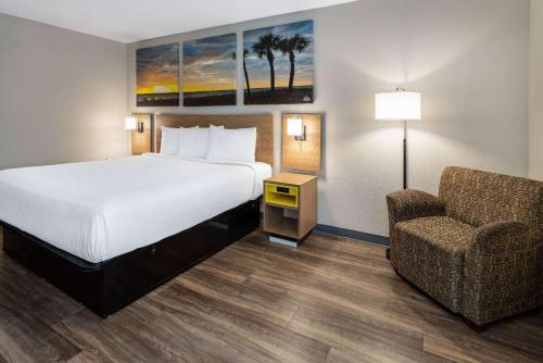 a hotel room with a bed and a chair at Days Inn by Wyndham Louisburg in Louisburg