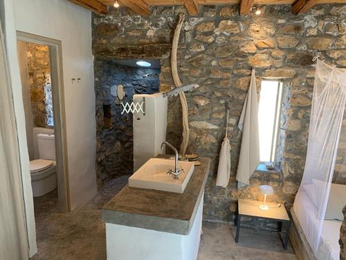 a bathroom with a sink and a stone wall at Mandri B&B in Serifos Chora