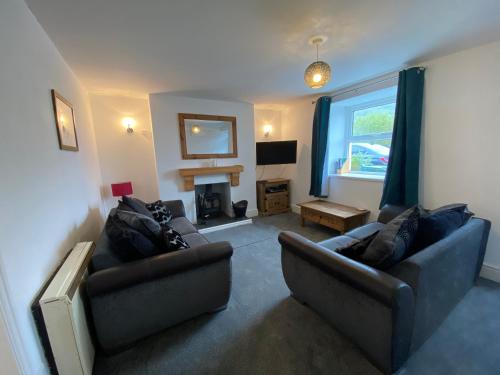 sala de estar con 2 sofás y chimenea en Antur Cottage en Blaenau-Ffestiniog