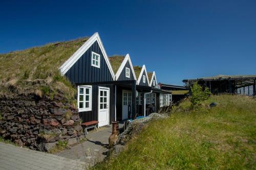 a black and white house with a grassy hill at Hlid Fisherman's Village in Álftanes