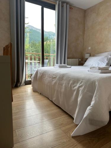 a bedroom with a white bed and a large window at Hotel Edelweiss in Auron