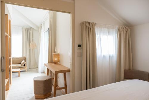 a bedroom with a bed and a desk and a window at Hôtel Ibaia in Hendaye