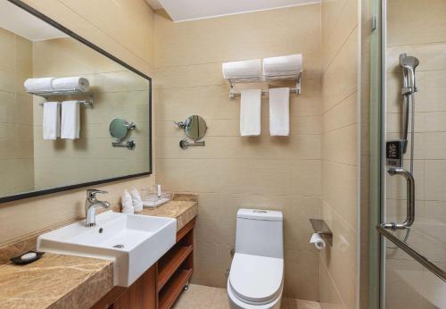 ein Badezimmer mit einem Waschbecken, einem WC und einem Spiegel in der Unterkunft Days Hotel by Wyndham Dali High-speed Railway Station in Dali