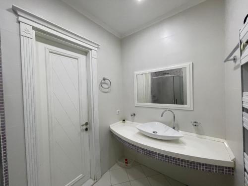 a white bathroom with a sink and a mirror at Studio Apartment in Baku
